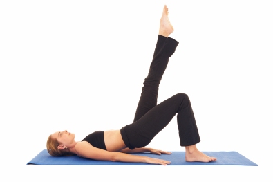 Fit young brunette pilates instructor showing different exercises on a white background a blue yoga mat. White background NOT ISOLATED